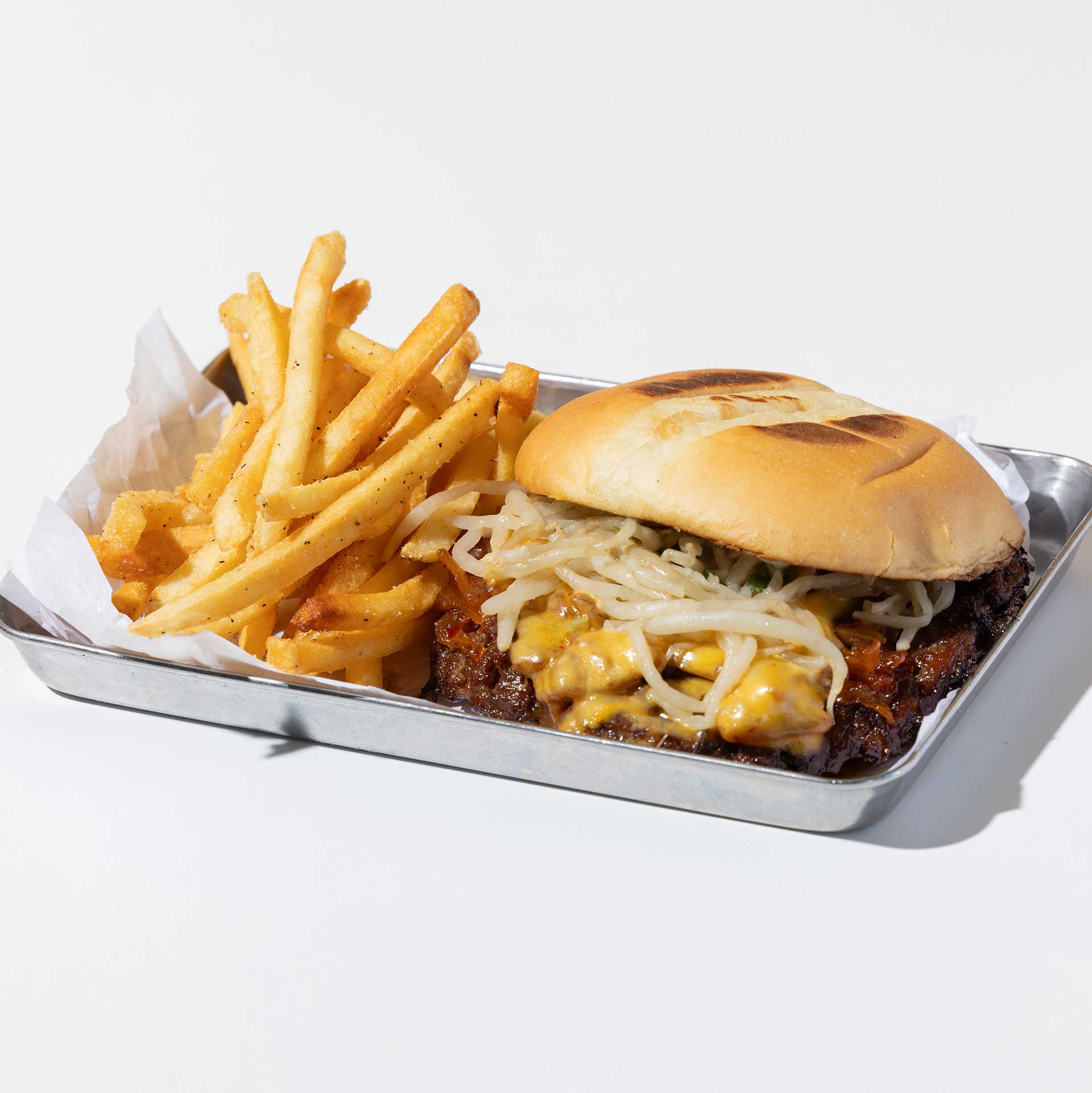 silver tray containing a bulgogi smash burger on a brioche bun with fries