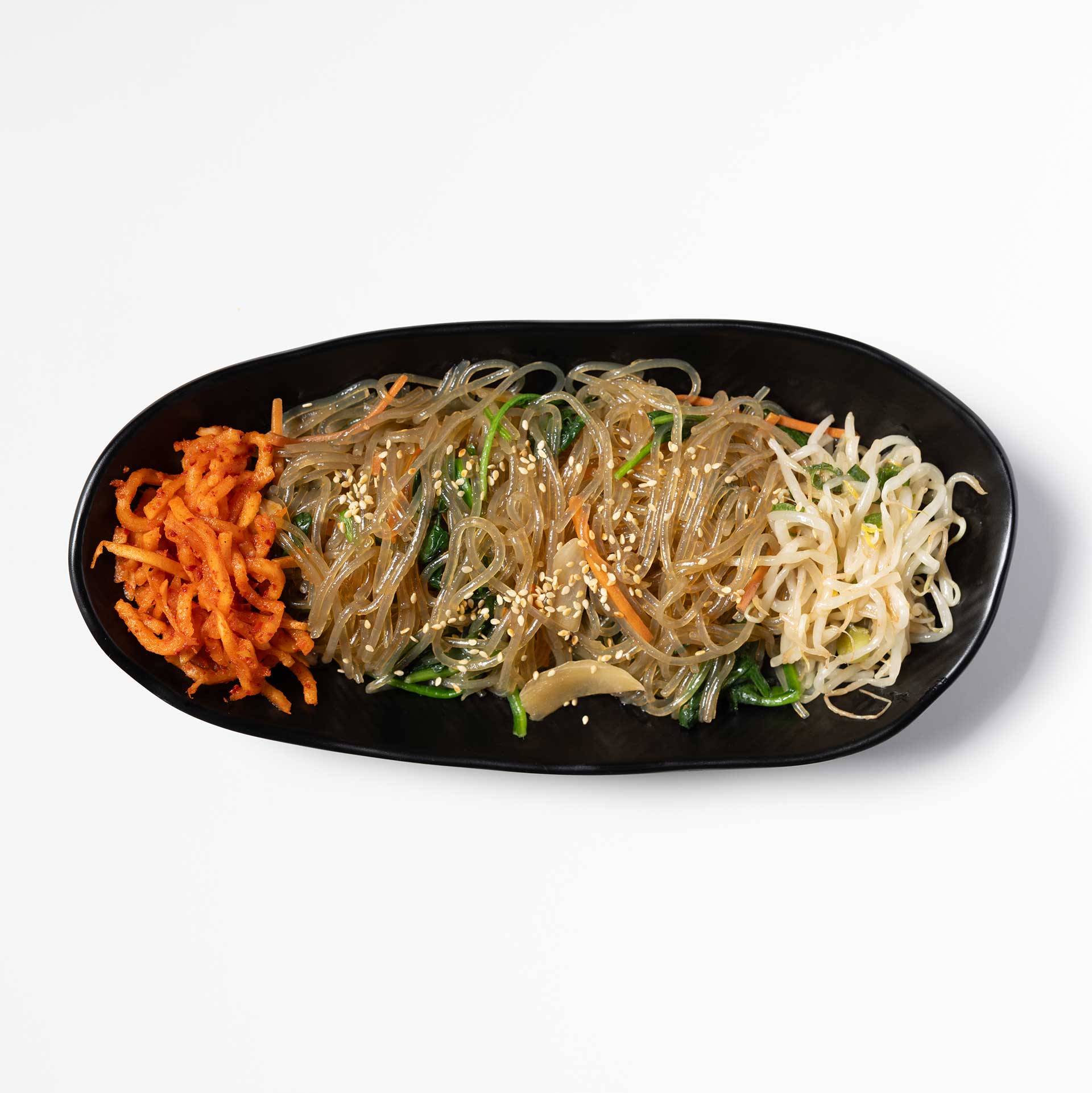 a black oblong plate containing japchae, which is potato starch noodles stir fried with mixed vegetables