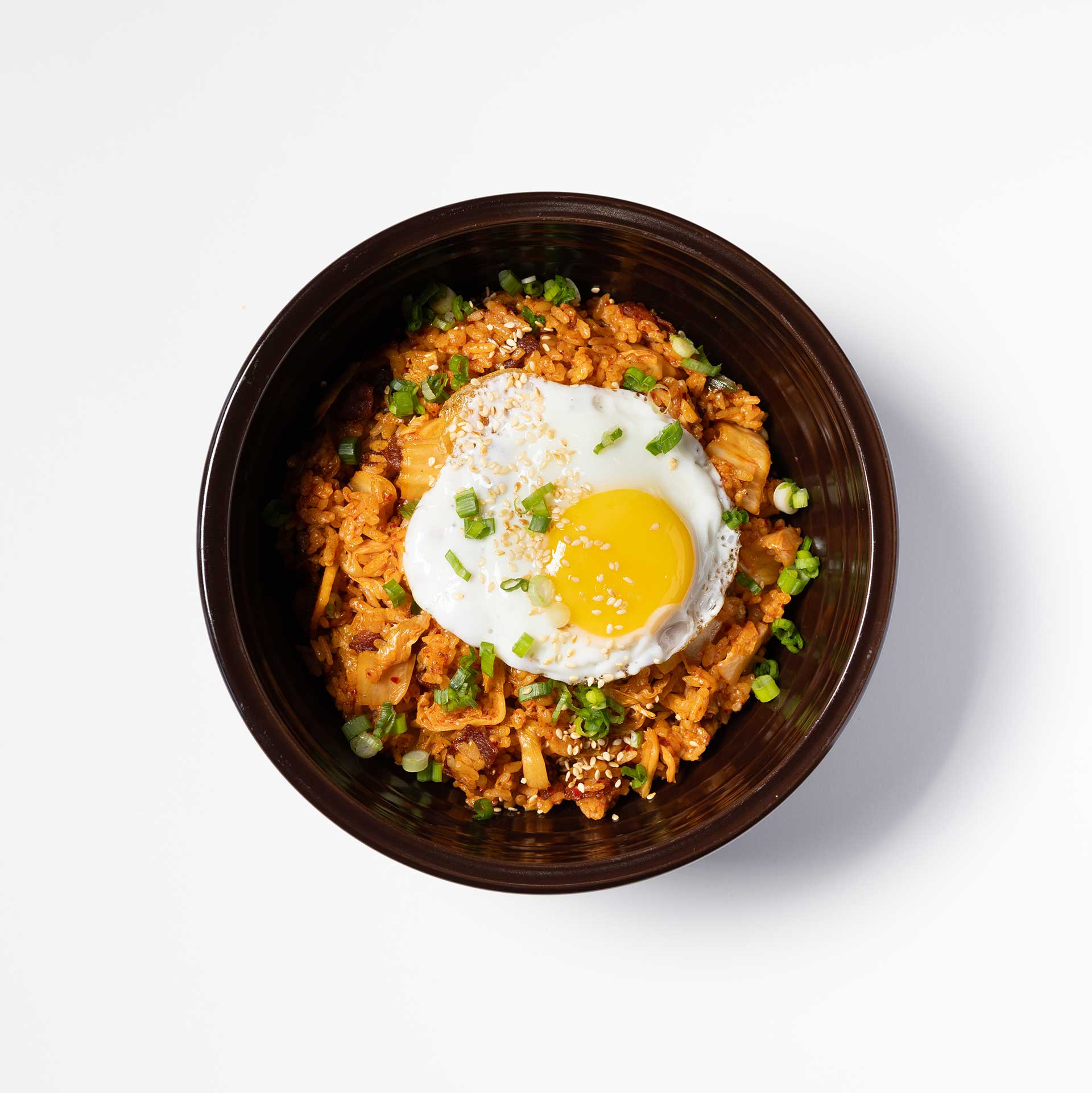 a black bowl containing kimchi fried rice topped with an egg